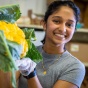 UB student Srikrithi Krishnan, a master’s student in the School of Public Health and Health Professions, bags fresh, in-season produce for the Food Box initiative in July 2023. The group is partnering with FreshFix, a local food distributor, to bring food to people experiencing food insecurity. Photographer: Douglas Levere. 