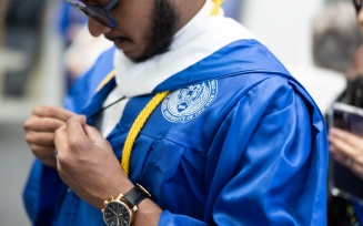 close-up view of student adjusting graduation gown. 