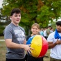 students standing outside, one holding a colorful beach ball. 