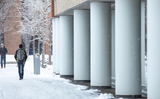 Students walking alongside Greiner Hall on a winter day. 