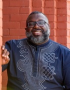 man with glasses smiling to the camera.