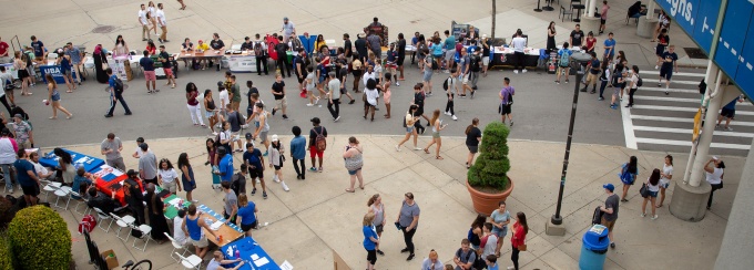 Rows of tables lining the sidewalk and traffic circle for new student orientation.