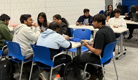 UB students sitting at a table enjoying snacks and engaging in conversation.