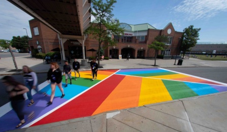 A crosswalk painted in a rainbow herringbone pattern on Putnam Way between the Student Union and the Commons.