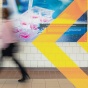 Person walking past photos of nanochemistry, biological and medicinal chemistry and synthesis in the Natural Sciences Complex at the University at Buffalo. 