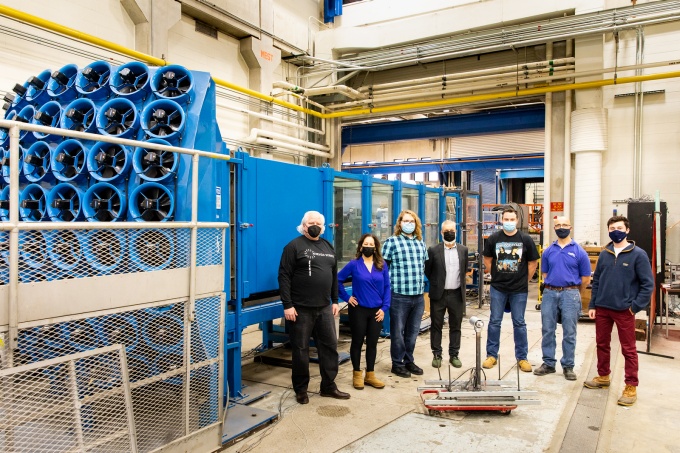 The Atrevida Science team stands in front of a wind tunnel in the Structural Engineering and Earthquake Simulation Laboratory in Ketter Hall in December 2021. UB spinoff Atrevida Science aims is developing dynamic wind turbine blades that automatically adjust to real-time changes in wind speed and direction. Left to right: Edward Tierney, PhD student James Roetzer, Claudia Maldonado (founder and CEO), John Hall, and student Cam Hotto.