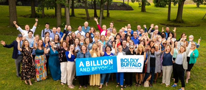 A large group poses with a sign saying, "A billion and beyond! Boldly Buffalo: The Campaign for UB".