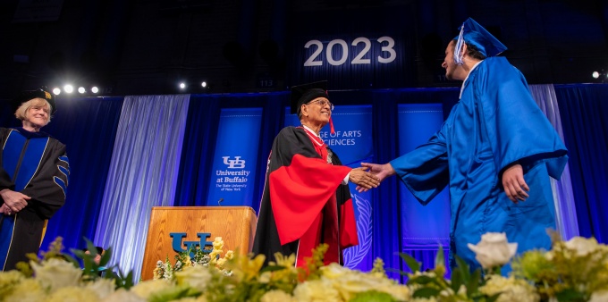 President Satish K. Tripathi shakes hands with a UB graduate as they cross the stage.
