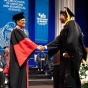 President Satish K. Tripathi shakes hands with a graduate as they cross the stage. 