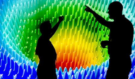 two people standing in front of a wall of computer images.