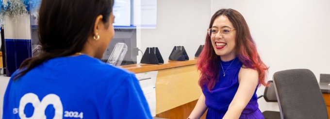Person smiling at another person at a service counter.