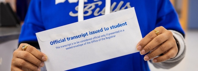 Person holding an envelope that says "Official transcript issued to student". 