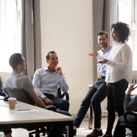 Royalty-free stock photo ID: 1212195550 Smiling african manager coach speaking at diverse corporate group meeting, female black teacher team leader talking to office workers at training teaching employees explaining new idea, mentoring.