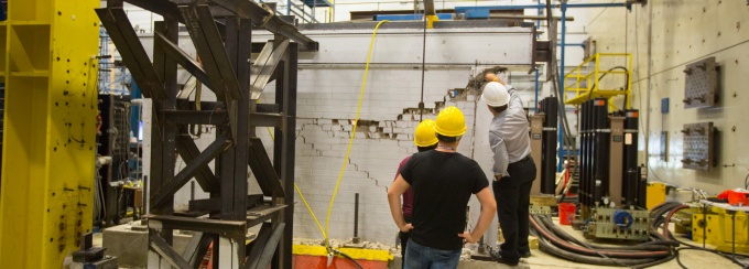 students and faculty examining cracks in a wall in the earthquake testing section of Ketter Hall.