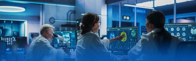 Researchers collaborating and reviewing brain scan on a screen.