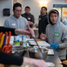 A group of students learning how to cook a meal together in the South Lake Village community room. 