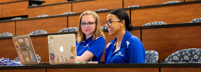 Two Orientation Leaders fill out online forms via their laptops.