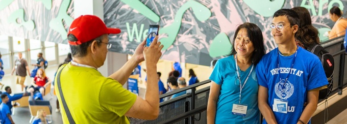 A new student poses for a picture with his parents or guardians.