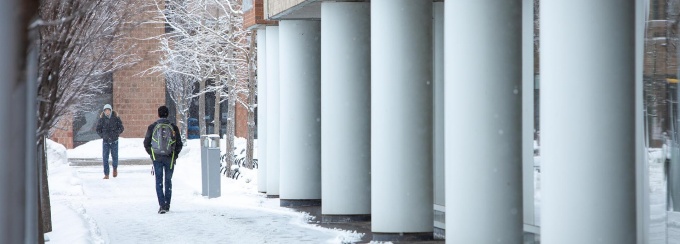 Students walking alongside Greiner Hall on a winter day.