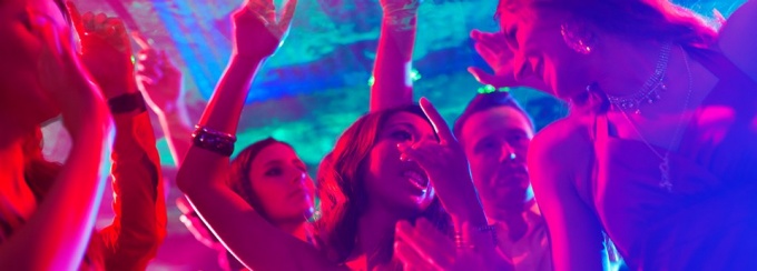 Students dancing at a party with purple and turquoise lighting.