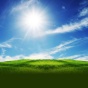 bright sun in blue sky over green grass. 