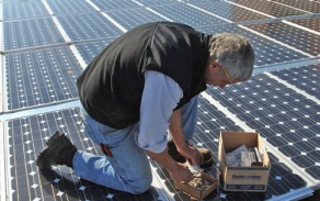 person bending over solar panels on roof.