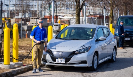 An electric car recharges at a charging station with man in the photo charging his car.