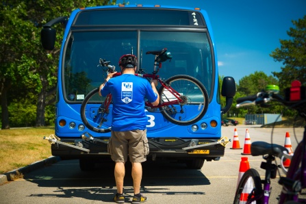 Man placing a bicycle on the front of a bus bike rack.