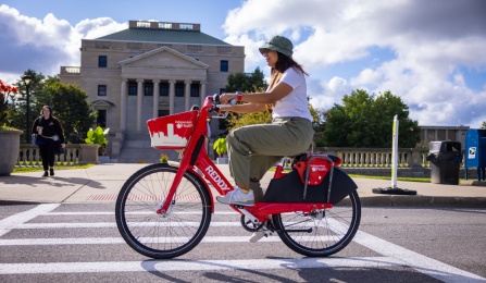 Student riding a red bike on south campus.