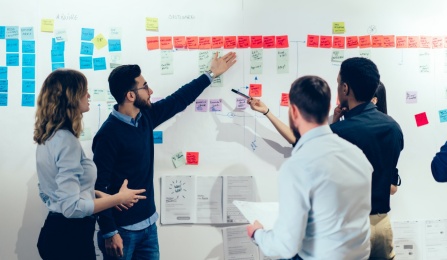 Male and female business people brainstorming with colorful sticky notes on the wall.