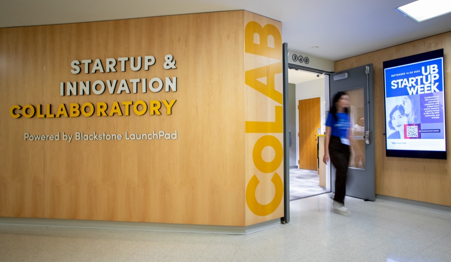 Exterior of the Startup & Innovation Collaboratory, Powered by Blackstone LaunchPad. Photo shows student walking out of the entrance. 