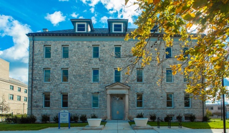 Exterior photo of Townsend Hall in the sunshine. A tree with yellow leaves stands in front of the left side of the building. 