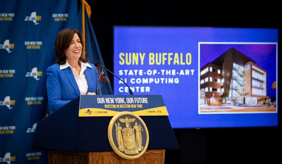 Governor Kathy Hochul stands at a podium during her visit to UB in January 2024. A screen behind her says, "SUNY Buffalo, State-of-the-art AI Computing Center". 