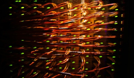 back shot of computer racks showing multiple connections among many racked computers.