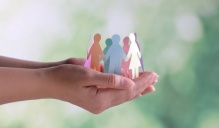 A photo of a circle of paper dolls in different colored paper held in a person's hands.