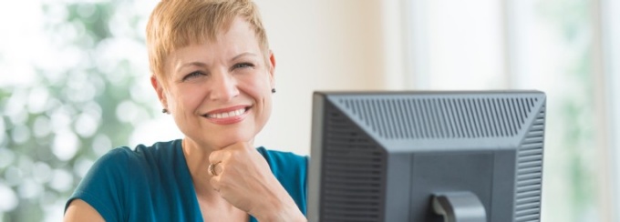 A woman at a desk is surrounded by screens and electronic devices.
