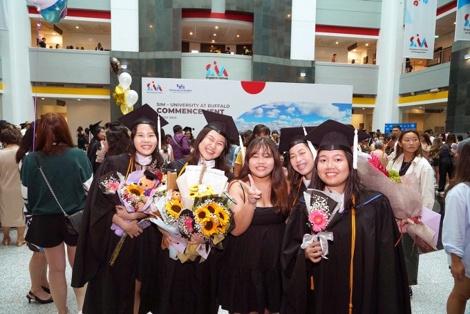 Group of graduates of the UB-Singapore program dressed in cap and gown. 