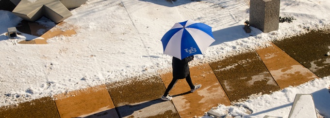 Student walking with UB umbrella.