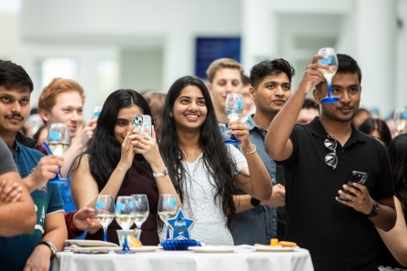 Students holding up glasses in celebration at the senior toast. 