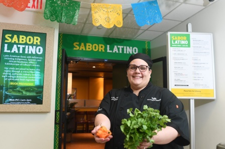 Chef Amelia Ruiz holding vegetables outside Sabor Latino restaurant.