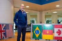 Chris Bragdon standing in a room with flags from multiple countries.