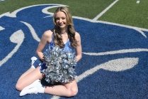 Emily Triquet, cheerleader, in her uniform on athletic field.