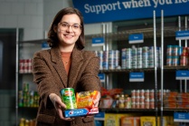 Brianna Bengert holding food and supplies in the Blue Table food pantry.