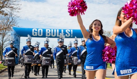 The UB Marching Band and the cheer team lead the way through the annual homecoming parade into UB Stadium. 