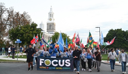 Students carrying the FOCUS parade banner and international flags. 